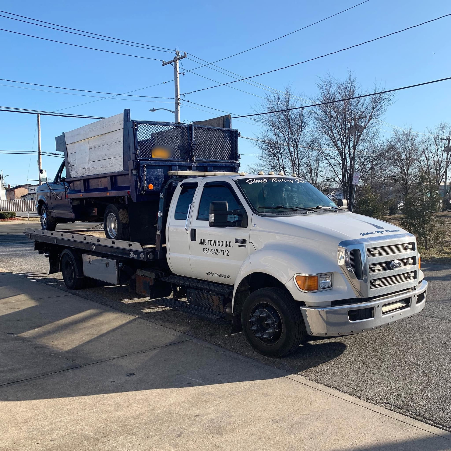JMB Towing flatbed truck hauling a dump-body pickup truck