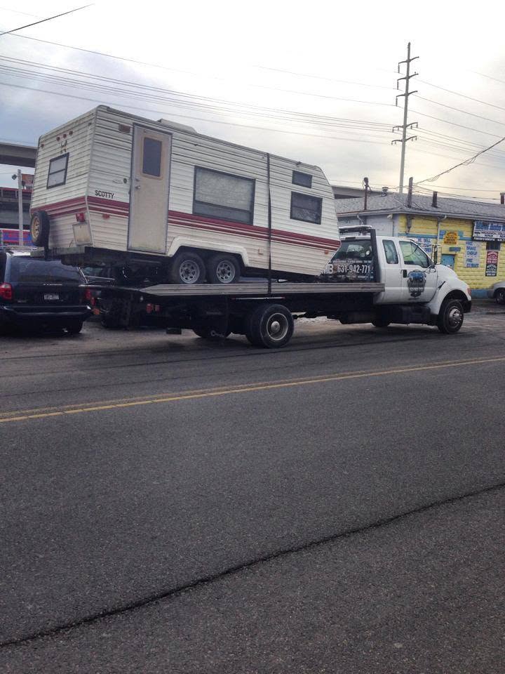 JMB Towing flatbed truck transporting a travel trailer