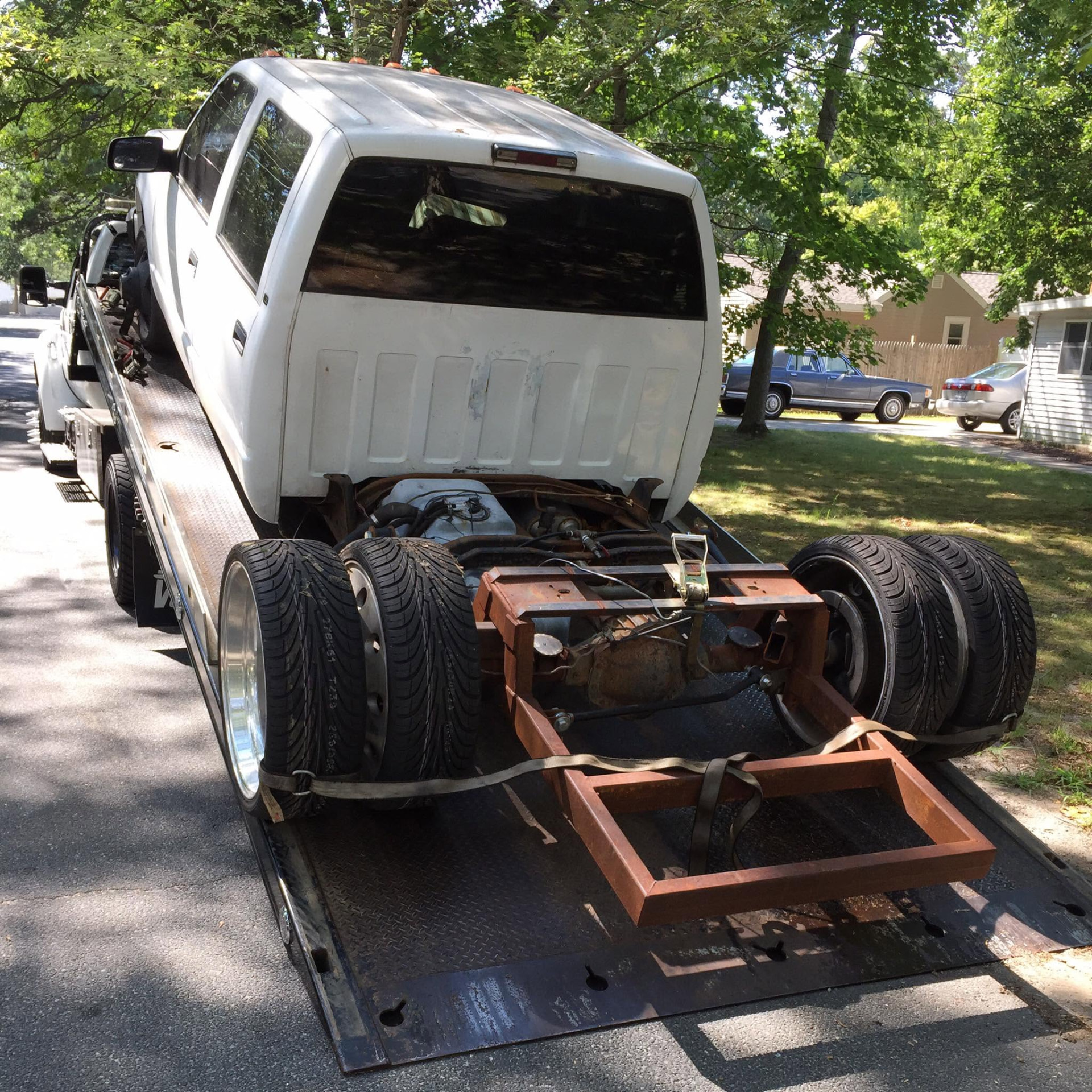 JMB Towing flatbed truck loaded with a project truck and spare tires